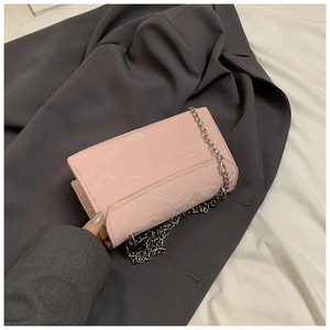 Détail du sac à main plissé brillant rose clair sur blazer gris avec chaîne argent