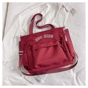 Détail du sac fourre-tout bordeaux en toile avec inscription et bandoulière réglable