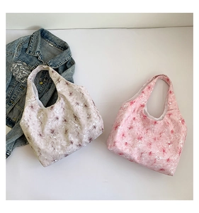 Détail de sacs fourre-tout en toile à imprimé floral mauve et rose posés sur veste en jean
