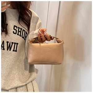 Détail du petit sac carré en cuir beige avec motif embossé et fermeture éclair métallique