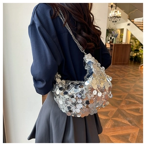 Close-up of a silver sequin crescent hobo bag with delicate metal chain strap on shoulder