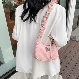 Pink pleated shoulder bag with butterfly metal ornament shown on a model in white blazer