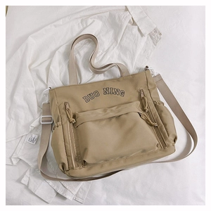 Détail du sac fourre-tout en toile kaki avec fermeture éclair frontale et broderie
