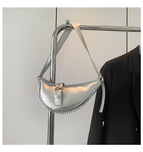 Détail du sac à main argenté en forme de croissant avec chaîne et boucle métallique