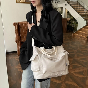Grand sac cabas en toile blanc cassé avec poches multiples et large bandoulière porté par modèle