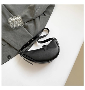 Détail du sac croissant noir minimaliste avec œillets métalliques et cuir mat lisse