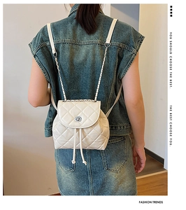 Rear view of a model wearing the cream quilted leather mini backpack with chain strap