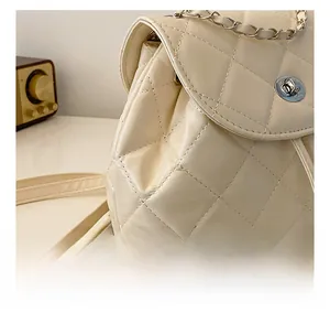 Detail view of cream quilted shoulder bag with silver turn-lock and chain strap