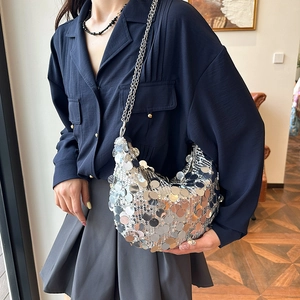 Chic silver sequin crescent moon bag with metal chain strap worn by a model in a home setting