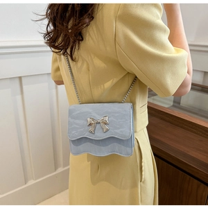 Detail of light blue mini bag with silver bow ornament and wavy flap edge design
