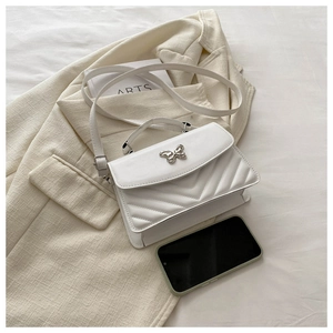 Detailed shot of white quilted leather crossbody bag featuring a silver butterfly clasp