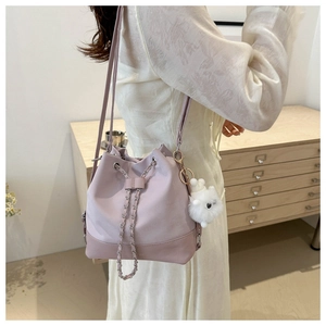 Detail of lavender drawstring bucket bag with metal chain and plush pompom accessory