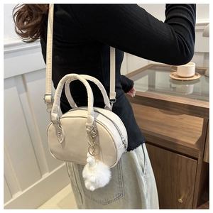 Détail du petit sac bowling blanc avec breloque en peluche et bandoulière réglable