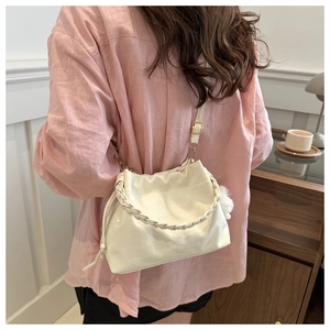 Sac seau blanc avec poignée tressée et breloque pelucheuse porté par un mannequin