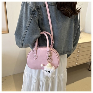 Détail d'un sac bowling rose avec deux poignées et charmant porte-clés monstre en peluche