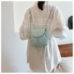 Detailed view of mint green quilted mini backpack featuring chain straps and metal twist lock