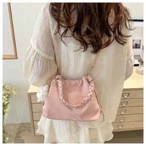 Détail du sac seau rose avec cordon de serrage, poignée tressée et pompon blanc