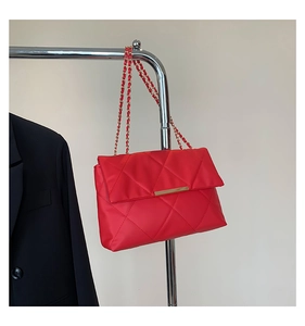 Detail of red quilted shoulder bag with gold metal trim and chain strap on a hanger