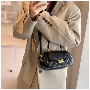 On-body view of a quilted shoulder bag with gold hardware on a khaki blazer
