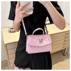 Detail of pink quilted square bag featuring a silver butterfly clasp on a black dress