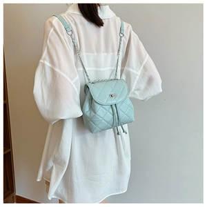 Close-up of mint green quilted mini backpack with silver chain strap worn by a model
