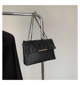 Detailed view of black quilted pattern with gold chain strap on a large shoulder bag