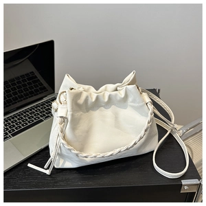 Gros plan du sac seau plissé blanc avec poignée tressée sur un bureau moderne