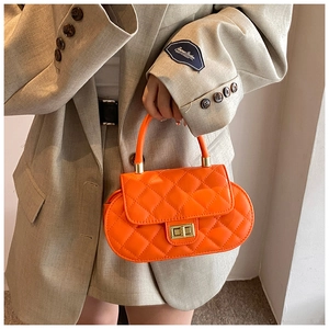 Detail of orange quilted leather handbag with gold metal lock held by a model