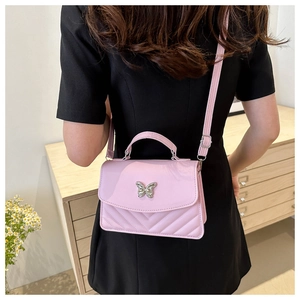 Detailed view of pink crossbody bag with silver butterfly buckle and V-shaped quilting