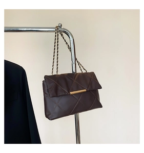 Detail of dark brown quilted shoulder bag featuring gold chain strap and metal lock
