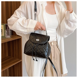 Detailed view of black quilted mini backpack with silver twist lock and chain strap