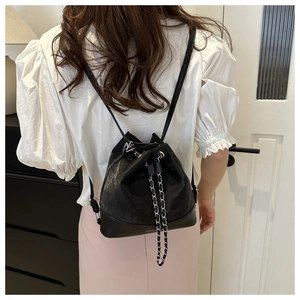 Detail view of large capacity black bucket backpack with silver chain and drawstring closure