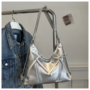 Detail of silver Y2K metallic shoulder bag with decorative bows and stylish zippers