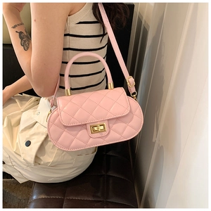 Pink quilted oval bag with gold twist lock and shoulder strap shown in a lifestyle setting