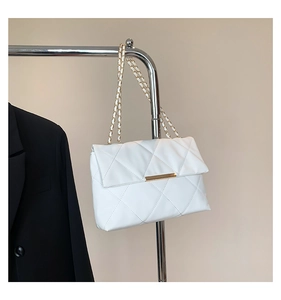 Detail of white quilted leather chain bag with gold metal clasp on a hanger