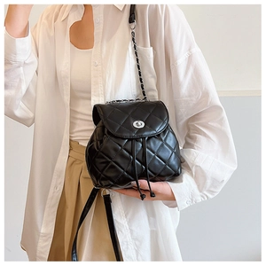Detail of a black quilted mini backpack with silver metal twist lock and chain strap