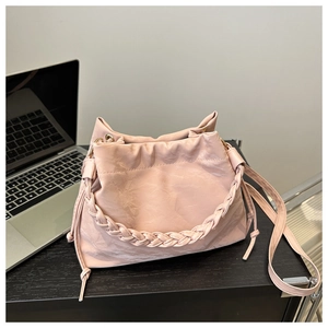 Détail du sac seau rose avec poignée tressée et bandoulière réglable en métal doré