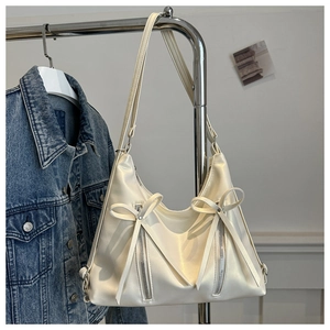 Detail of creamy white tote bag with twin bow accents and decorative metal zippers