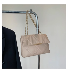 Detail of beige quilted shoulder bag with gold chain strap and metallic closure