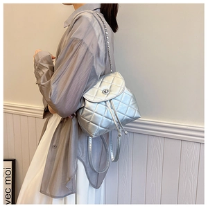 Silver quilted mini backpack with metal chain straps shown on model back profile