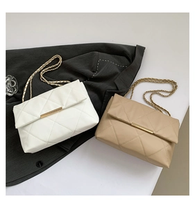 Detail of quilted leather crossbody bags with gold chain straps in white and beige colors