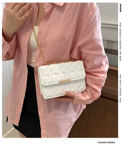 Close-up of white quilted crossbody bag featuring gold chain strap and metal clasp