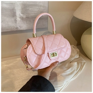 Detail of pink quilted handbag featuring a gold twist lock and rounded top handle design
