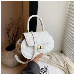 Detailed view of the gold twist lock and quilted embroidery on the white luxury handbag