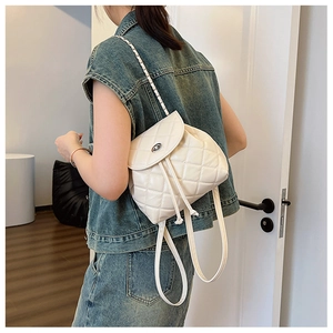 Close-up of quilted white leather backpack with silver chain strap and drawstring closure
