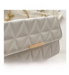 Detailed close-up of white quilted faux leather texture with elegant gold clasp and chain