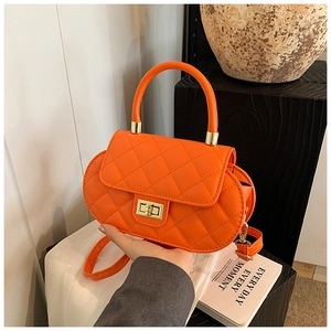 Detailed close-up of orange quilted leather handbag with gold turn-lock and handle