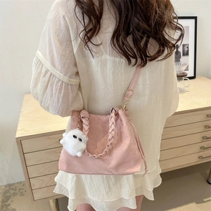 Sac seau rose avec poignée tressée et pendentif monstre en peluche en usage quotidien