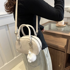 Sac bowling beige minimaliste avec doubles poignées et breloque peluche, vue en bandoulière