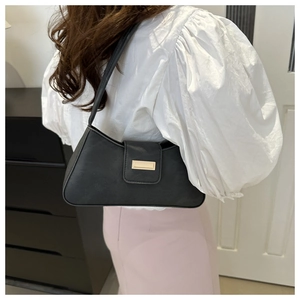 Close-up of sleek black faux leather baguette bag featuring a polished gold buckle detail